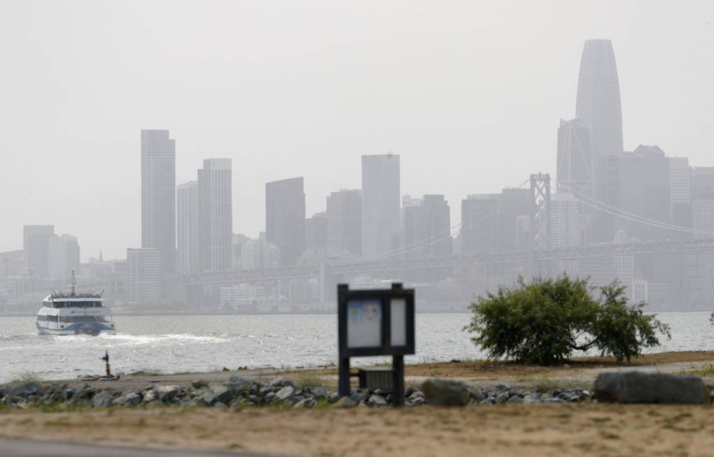 hazy skyscrapers in the distance with a ferry boat in foreground