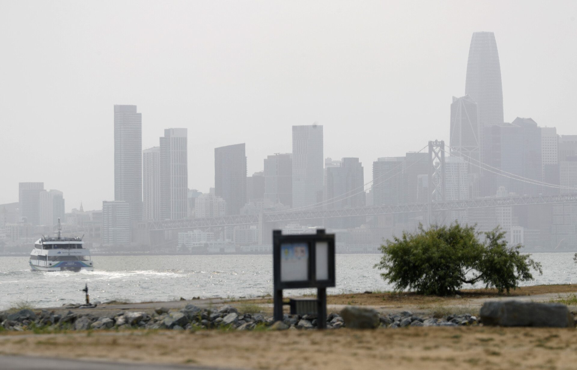 hazy skyscrapers in the distance with a ferry boat in foreground