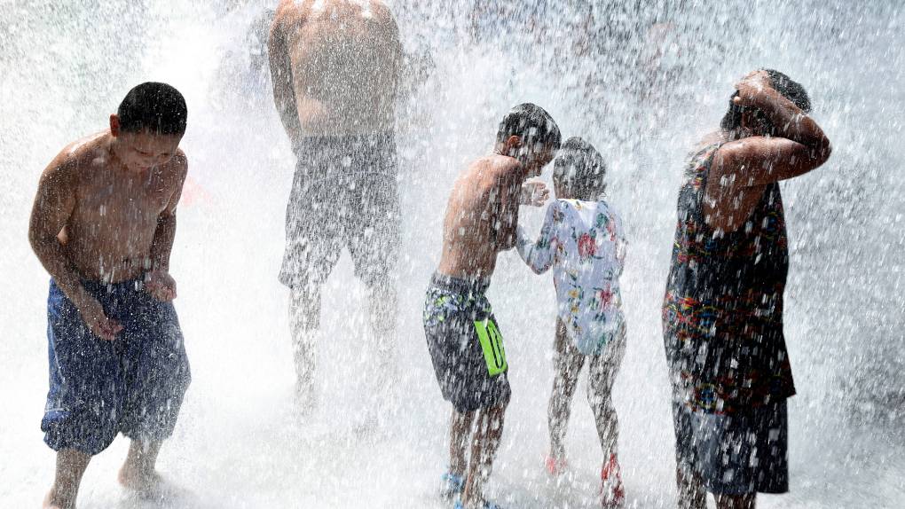 Young kids in swimwear getting soaked by falling water