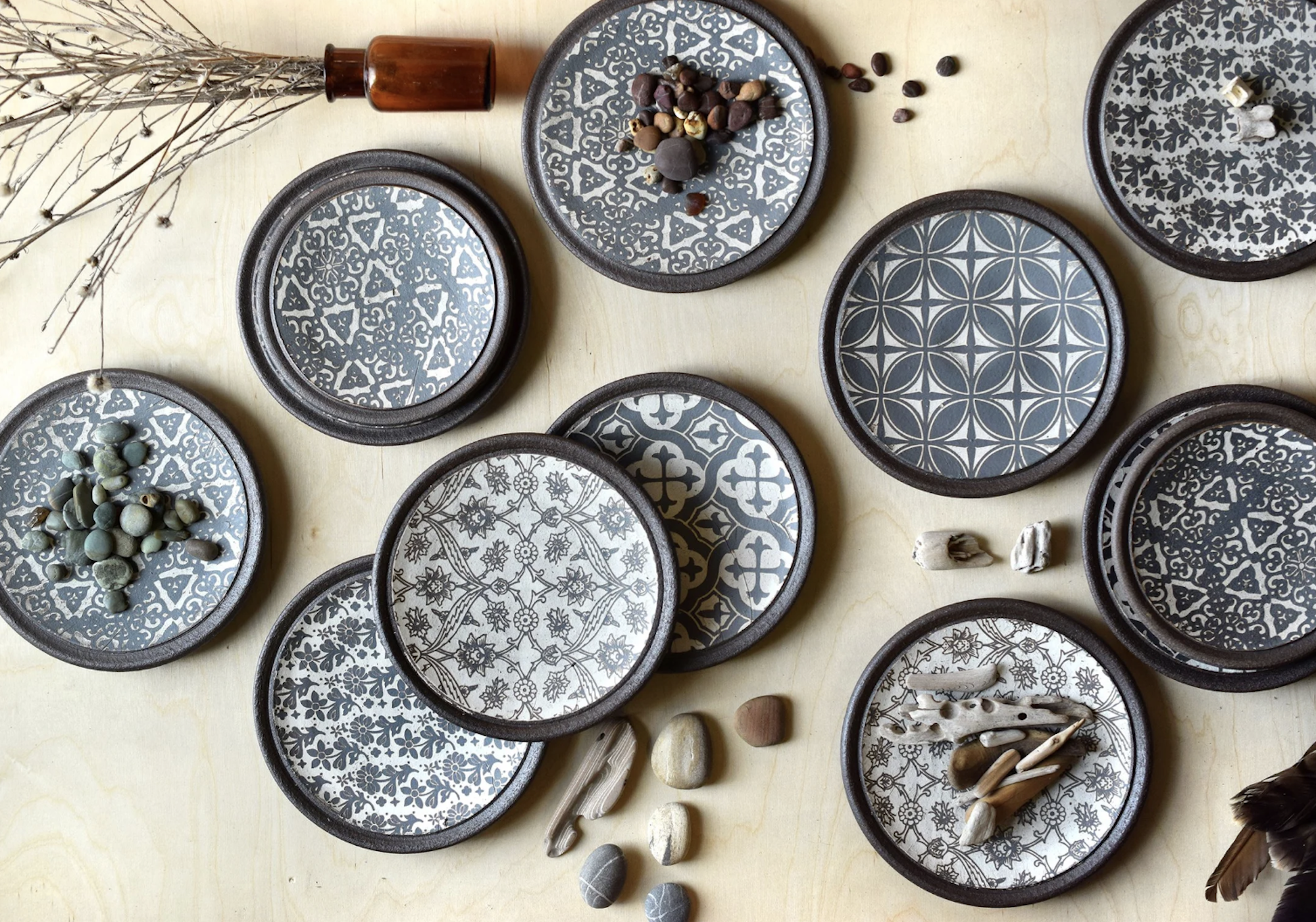 Eleven plates featuring geometric patterns in grey and white. 
